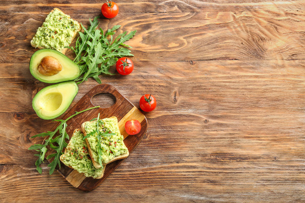 Composition with tasty avocado and sandwiches on wooden background - Photo, Image