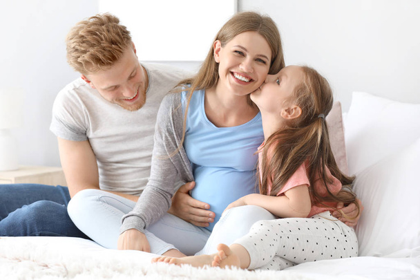 Kaunis raskaana oleva nainen perheensä kanssa makuuhuoneessa
 - Valokuva, kuva