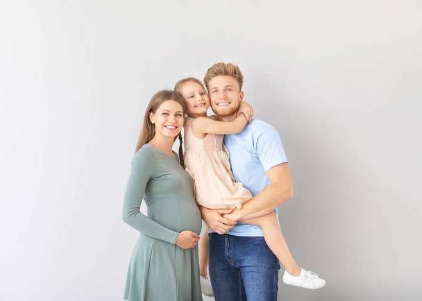 Belle femme enceinte avec sa famille sur fond clair
 - Photo, image
