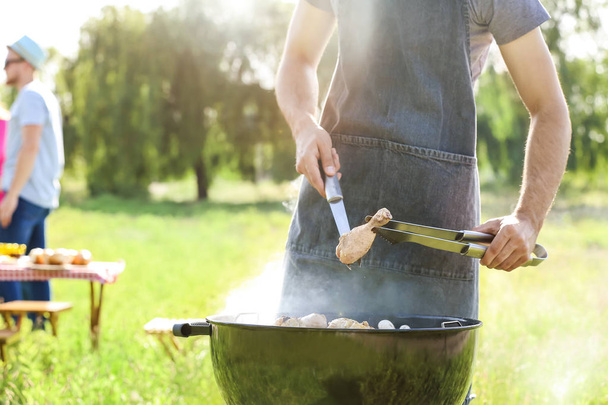 Мужчина готовит вкусную еду на гриле на открытом воздухе
 - Фото, изображение