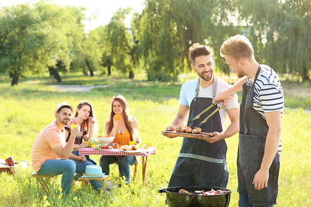 Friends cooking tasty food on barbecue grill outdoors - Photo, Image