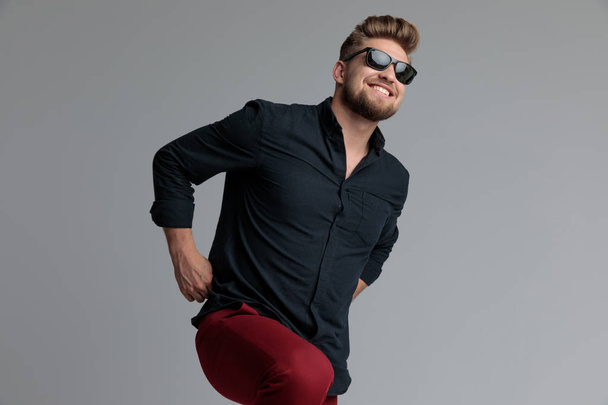 Pozitivní příležitostný muž, který se směje a vytahuje si červené kalhoty  - Fotografie, Obrázek