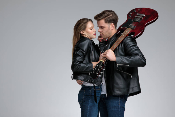 Vášnivý muž objímá svou přítelkyni a drží kytaru - Fotografie, Obrázek