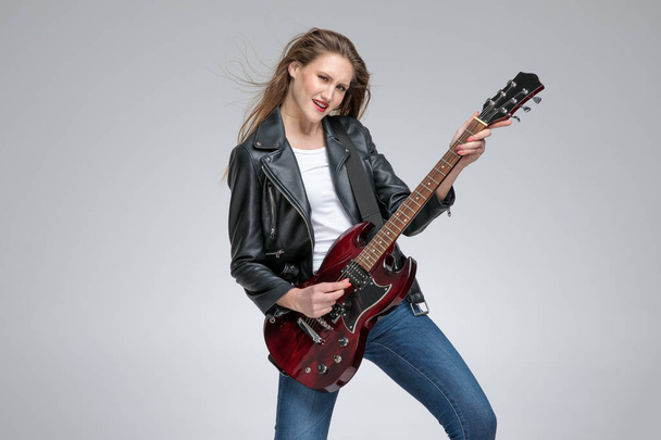 Chica joven apasionada tocando la guitarra y con un jacke de cuero
 - Foto, Imagen