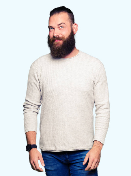 Νέος ξανθός άντρας φορώντας casual πουλόβερ χαμογελαστός κοιτάζοντας πλευρά και κοιτάζοντας μακριά σκέψης. - Φωτογραφία, εικόνα