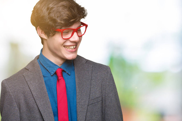 Young handsome business man wearing red glasses over isolated background looking away to side with smile on face, natural expression. Laughing confident. - Fotografie, Obrázek