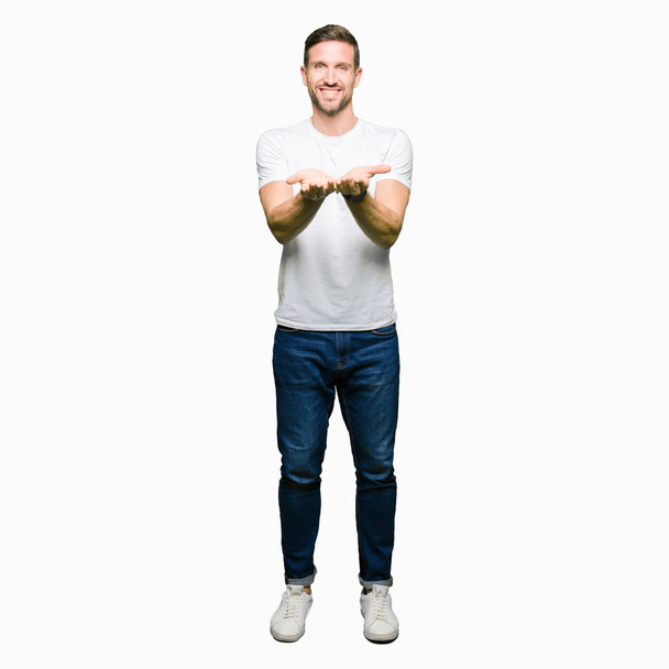 Noszenie na co dzień biały t-shirt Smiling dłońmi ręce razem odbieranie lub dając gest przystojny mężczyzna. Przytrzymaj i ochrony - Zdjęcie, obraz