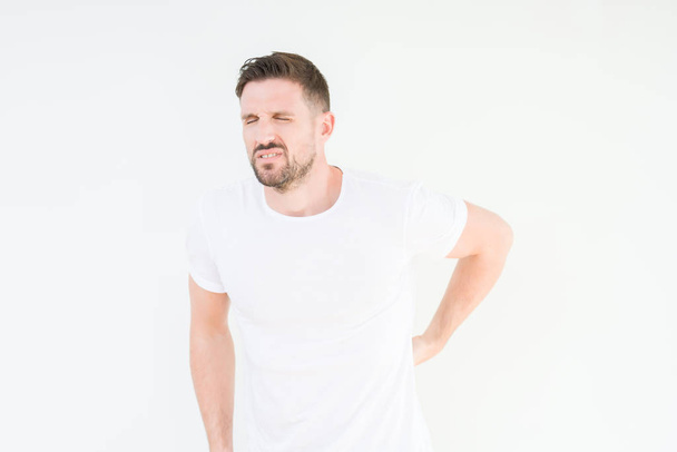 Young handsome man wearing casual white t-shirt over isolated background Suffering of backache, touching back with hand, muscular pain - Zdjęcie, obraz