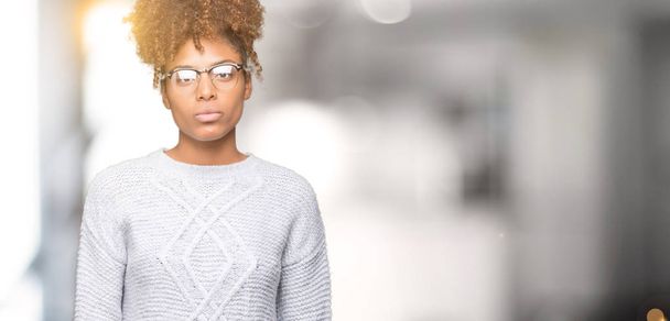 美しい若いアフリカ系アメリカ人女性の顔に真剣な表情で孤立した背景に冬のセーターを着ています。シンプルで自然なカメラを見てください。. - 写真・画像