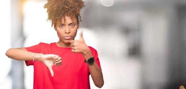 Красива молода жінка афро-американських над ізольованих фон робити пальці руки вгору і вниз, розбіжностей і угоди вираз. Божевільний конфлікт - Фото, зображення