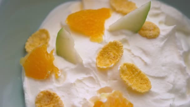 Closeup macro shoot of hand dipping a spoon in tasty yogurt breakfast bowl with fruits and cornflakes - Video, Çekim