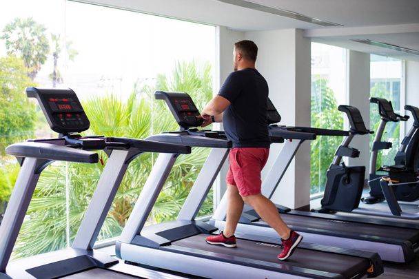 volle männliche läuft auf einem Laufband in einem Fitnessstudio. Konzept der Gewichtsabnahme und Sport. zurück. - Foto, Bild