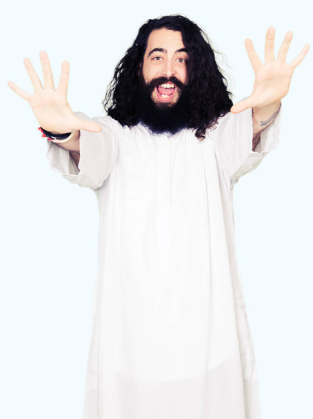 Hombre vistiendo traje de Jesucristo mostrando y señalando con los dedos número diez mientras sonríe confiado y feliz
. - Foto, Imagen