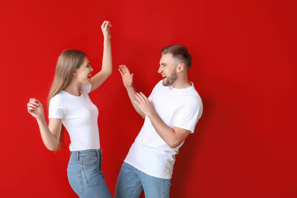 Portrait de jeune couple heureux dansant sur fond de couleur
 - Photo, image