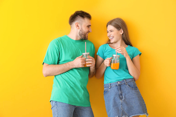 Portrait of young couple with cocktails on color background - Photo, image
