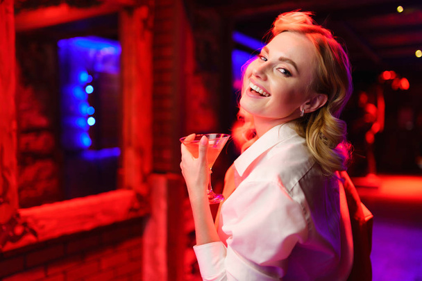Foto van gelukkig blond meisje met cocktail in haar hand bij Disco - Foto, afbeelding