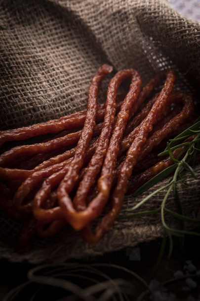 Thin sausages with herbs on a dark background. Rural meat.  - Фото, зображення