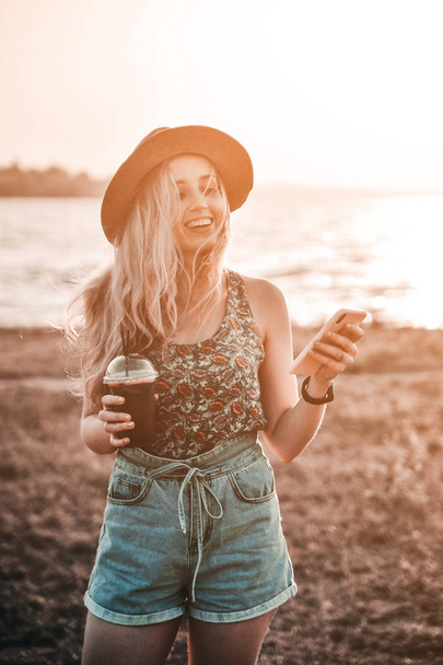 Beautiful young woman in stylish hat with summer cold cocktail has a fun outdoors. - Fotoğraf, Görsel