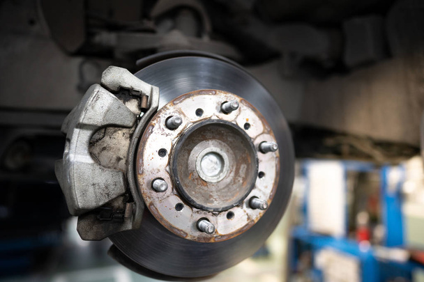 Fren disk onarım için aracın kapatın. Otomobil makinist yeni lastik değiştirme süreci. Garajda tamir araba fren. Araba servisi ve teknisyen kavramı. - Fotoğraf, Görsel