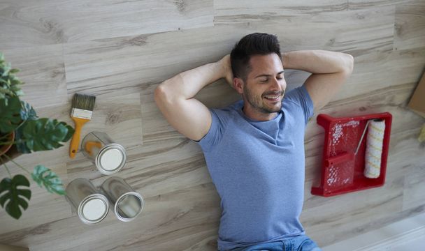 Lachende man die een korte pauze neemt tijdens het schilderen van zijn flat  - Foto, afbeelding