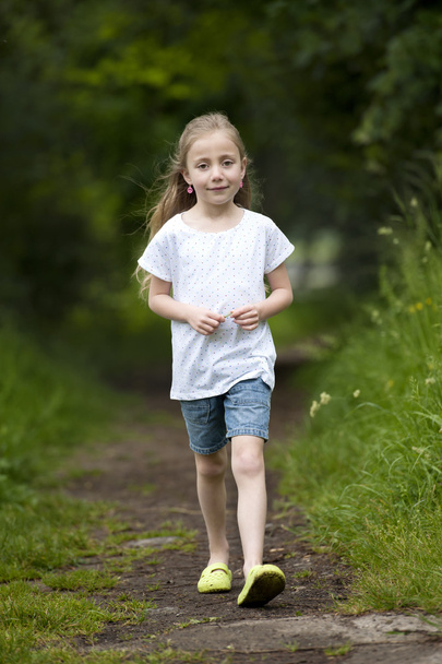 Summer holidays: Littel girl walking on a path in the woods - Foto, afbeelding