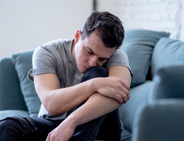 Portrait of young man felling depressed and desperate crying alone in sofa home suffering emotional pain and unhappiness. In People Broken heart, Bullying Depression and Mental health issues concept. - Photo, image
