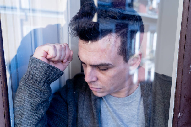 Bliska portret młody smutny niezadowolony kaukaski mężczyzna patrząc martwi, zdesperowany i samobójcze przez okno w domu. uczucie, bezwartościowe i w bólu. W koncepcji osób, depresji i kryzys. - Zdjęcie, obraz
