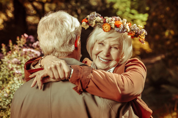 Cheerful elderly woman hugging her husband in a park. - Фото, зображення