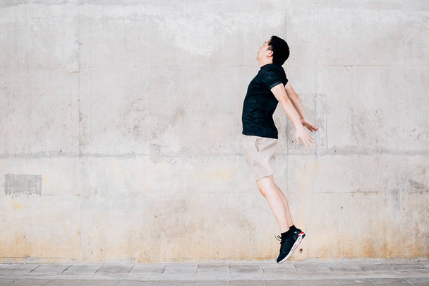 Asian sportsman jumping against wall - 写真・画像