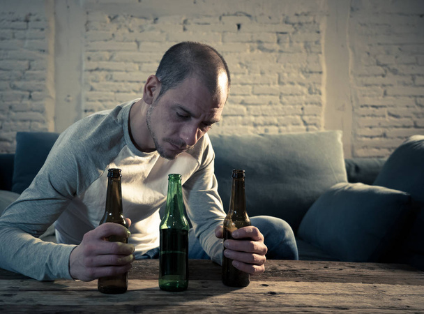 Young sad drunk men drinking beer and alcohol feeling wasted, lonely and desperate in pain and emotional stress. People and Alcohol abuse, addiction and man depression concept. Dramatic light - Foto, Bild