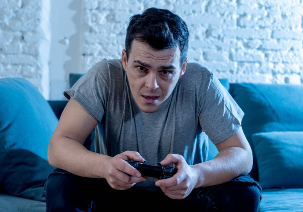 Portrait of young student man spending time playing video games using wireless remote joystick with freak intense happy face having fun in Male game addiction to console play station and video. - Fotó, kép