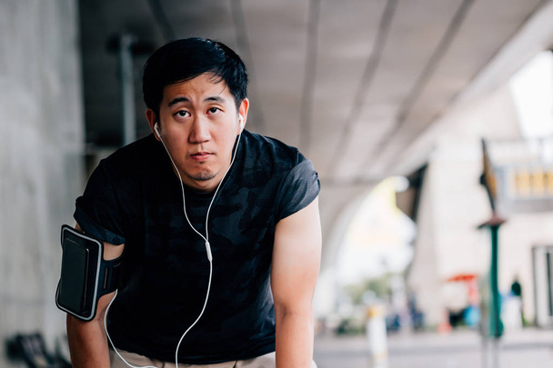 Tired Asian man jogging on street - Fotó, kép
