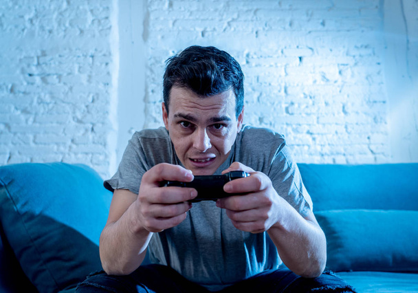 Portrait of young student man spending time playing video games using wireless remote joystick with freak intense happy face having fun in Male game addiction to console play station and video. - Фото, изображение