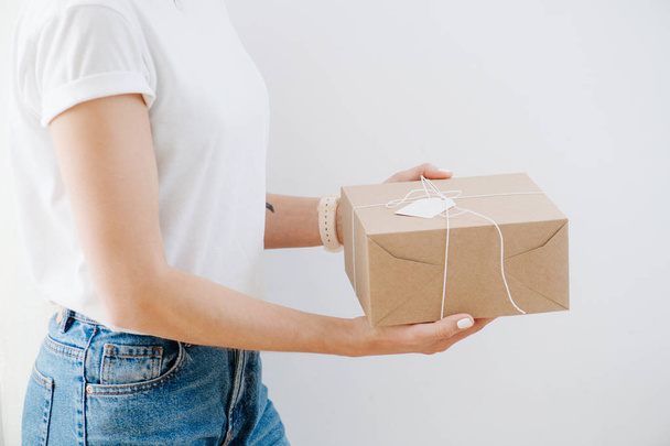 Portrait of a woman in casual clothes presenting postal cardboard box - Photo, Image
