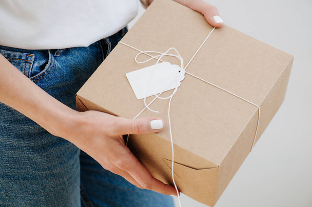 Portrait of a woman in casual clothes holding postal cardboard box - Foto, Imagen