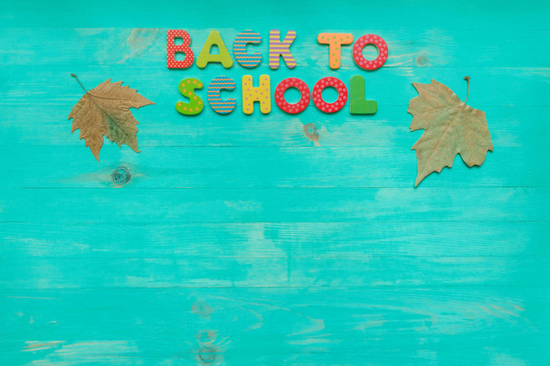 学校の概念に戻る。カラフルなテキストと秋の乾燥した葉のバナーのトップビューは、コピースペースと木製の背景の上に. - 写真・画像