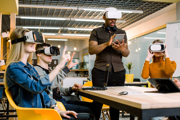 Group of positive colleagues testing virtual reality glasses. Handsome African businessman developing a project using virtual reality goggles. - Fotoğraf, Görsel