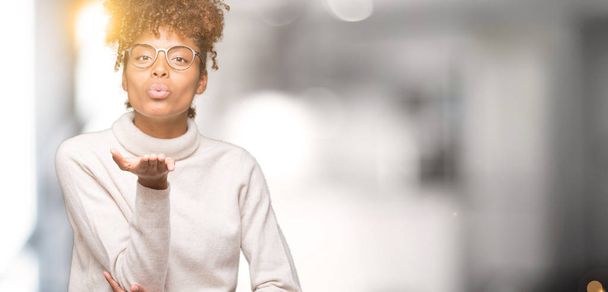 Красива молода афро-американських жінка в окулярах над ізольованих фону, дивлячись на дме поцілунку з боку повітря, будучи мила й сексуальна камери. Вираження любові. - Фото, зображення