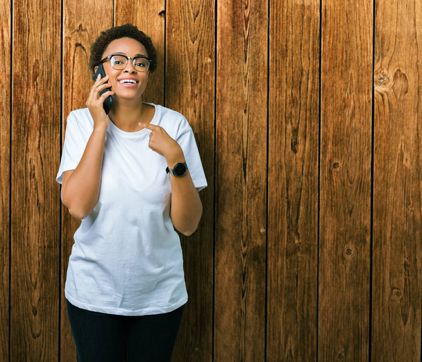 自分自身に驚き顔ポインティング指で孤立した背景に、電話で話している若いアフリカ系アメリカ人女性 - 写真・画像