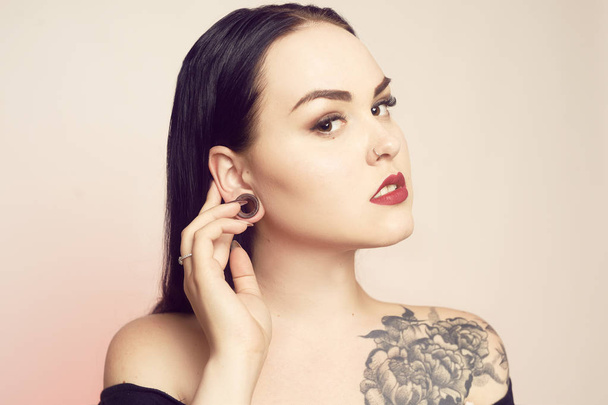 Portrait of a brunette with a tunnel in her ears, and a pierced  - Photo, Image
