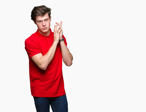 Young handsome man wearing red t-shirt over isolated background Holding symbolic gun with hand gesture, playing killing shooting weapons, angry face - Valokuva, kuva
