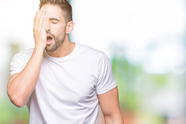 Handsome man wearing white t-shirt over outdoors background Yawning tired covering half face, eye and mouth with hand. Face hurts in pain. - Φωτογραφία, εικόνα