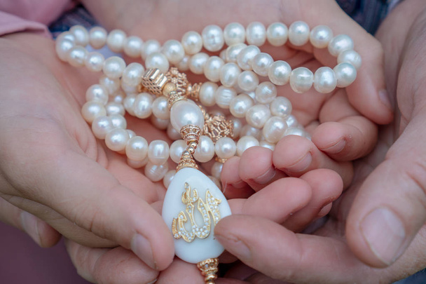 Una anciana y una niña están sosteniendo un bello rosario blanco. Manos de una anciana y una niña con rosario de perlas de cerca. Concepto religioso
 - Foto, imagen