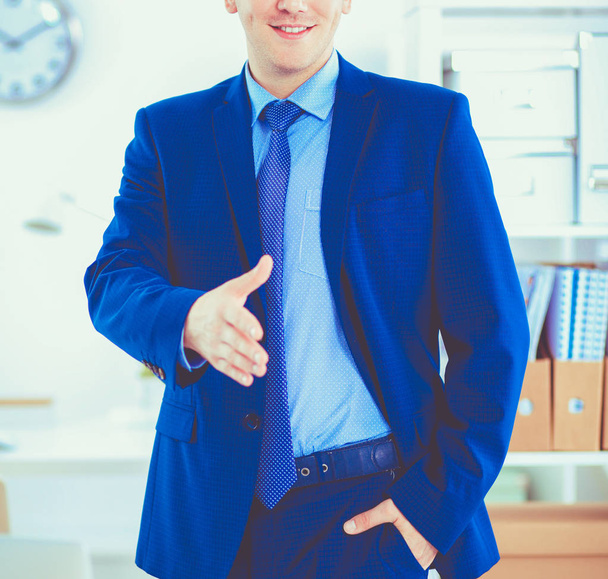 Successful business man standing in office giving hand - Foto, imagen