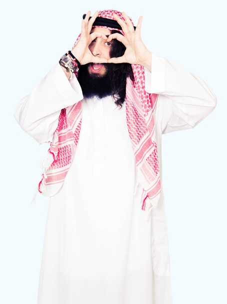 アラビア ビジネスの男性と伝統的なクーフィーヤ スカーフ手と指の標識を見て笑みを浮かべてやってハートを身に着けている長い髪 - 写真・画像