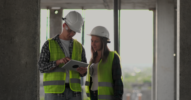 Bouwwerf team of architect en bouwer of werknemer met helmen Bespreek op een steigerbouw plan of blauwdruk of checklist. - Video