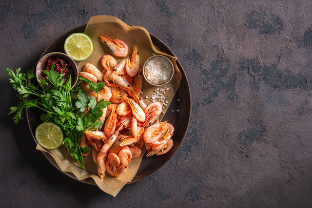 Raw shrimp in a pan with ingredients for cooking on a dark background top view - Foto, imagen