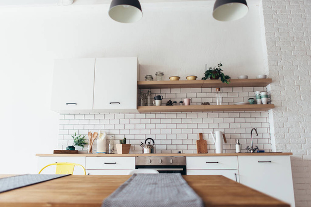 Μοντέρνο νέο φως εσωτερικό της κουζίνας με λευκά έπιπλα και τραπεζαρία. - Φωτογραφία, εικόνα