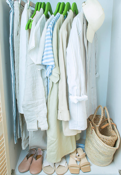 summer wardrobe with linnen clothes on green hangers - Φωτογραφία, εικόνα