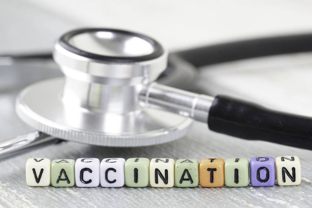 Vaccination wording from an alphabet beads and stethoscope on a wooden surface. selective focus  - Photo, image